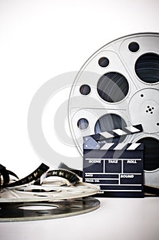 Movie clapper and vintage 35 mm film cinema reel on white