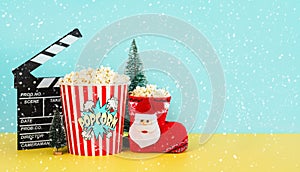 Movie clapperboard with popcorn,christmas ornament,snowflakes and space for text. Christmas movies concept