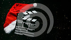 Movie clapperboard with Santa`s hat and sparkling glitter with space for text. Christmas movies concept