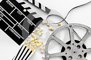 Movie premiere concept with clapperboard, film type, popcorn on white background top view