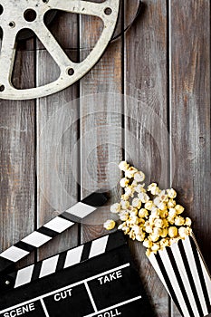 Movie premiere concept with clapperboard, film type, popcorn on wooden background top view