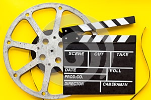 Movie premiere concept with clapperboard, film type on yellow background top view