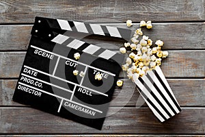 Movie premiere concept with clapperboard, popcorn on wooden background top view