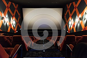 Movie screen and red chairs inside of a cinema