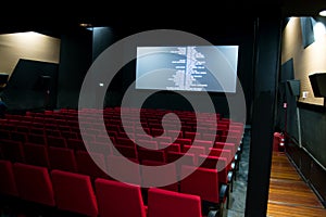 Movie screen and red chairs inside of a cinema