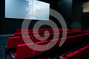 Movie screen and red chairs inside of a cinema