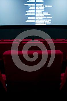 Movie screen and red chairs inside of a cinema