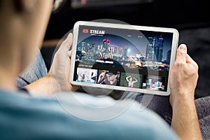 Movie and series stream VOD service in tablet. Watching on demand tv show or film online. Man choosing video entertainment.