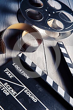 Movie slate and film reel on wood
