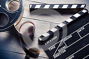 Movie slate and film reel on wood