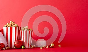 Movie-themed setup displaying striped popcorn containers, holiday ornaments, Santa\'s ha against a red wall