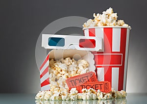 Movie tickets, popcorn and 3D glasses on a gray