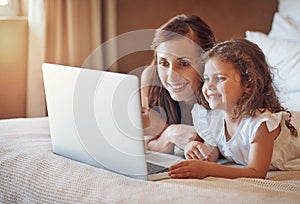 Movie time with Mom. Shot of a mother and her little daughter using a laptop together at home.