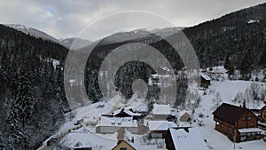Moving 4K drone flight over the skiing resort village. Aerial winter landscape with small village houses between snow