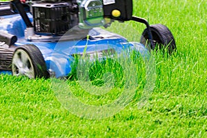 Moving Blue Lawnmover Cutting Green Grass photo