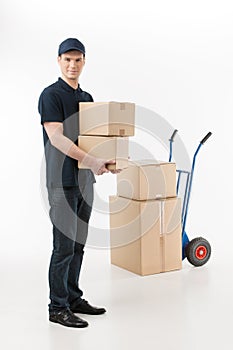 Moving boxes. Full length of young deliveryman holding a stack o