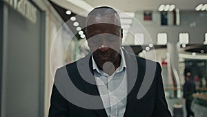 Moving camera shot African American middle-aged man adult 50s businessman indoors in mall shopping center company
