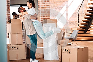 Moving, cardboard boxes and couple hug in new home for property investment, real estate or renting. Homeowner, happy man