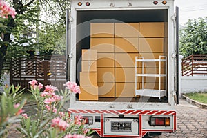 Moving cardboard boxes in an open car trunk outdoors. White delivery van for