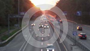 Moving cars on the motorway during sunset. Busy traffic on a freeway or highway, top view of the road. Scenic shot of trucks and c