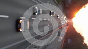 Moving cars on the motorway during sunset. Busy traffic on a freeway or highway, top view of the road. Scenic shot of trucks and c