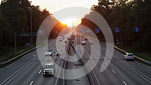 Moving cars on the motorway at sunset time. Highway traffic at sunset with cars. Busy traffic on the freeway, road top view