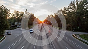 Moving cars on the motorway at sunset time. Highway traffic at sunset with cars. Busy traffic on the freeway, road top view