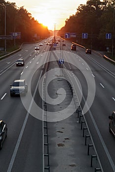 Moving cars on the motorway at sunset time. Highway traffic at sunset with cars. Busy traffic on the freeway, road top view
