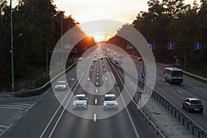 Moving cars on the motorway at sunset time. Highway traffic at sunset with cars. Busy traffic on the freeway, road top view