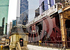 Moving commuter el train crosses over Lake Street and Chicago River alongside a bridgehouse