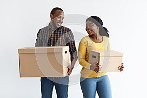 Moving Concept. Happy Young Black Man And Woman Carrying Cardboard Boxes