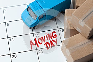 Moving day on the calendar is written in red. Calendar with a note with cardboard boxes and truck.