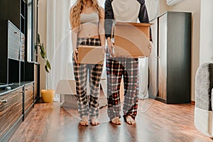 Moving day. Happy couple in their new apartment is having fun with cardboard boxes. Cheerful young couple in new house at moving