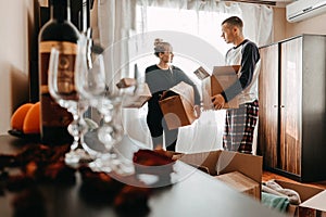 Moving day, new home, unpacking boxes. Happy couple in their new apartment is having fun with cardboard boxes. Cheerful