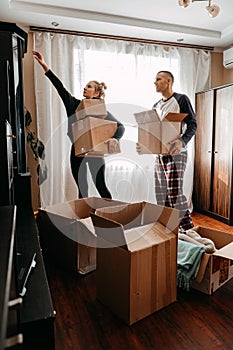 Moving day, new home, unpacking boxes. Happy couple in their new apartment is having fun with cardboard boxes. Cheerful