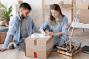 moving day and relocation concept, man and woman packing cardboard boxes to new house on moving day