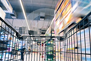 Moving empty black shopping cart with motion in the supermarket aisle, customer choosing product on market shelf store