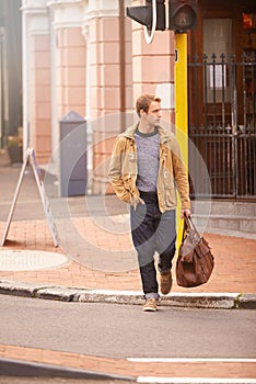 Moving on. Full length shot of a fashionable man crossing a street in the city.