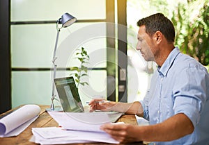 Moving from hardcopy to digital. a young man working from home.