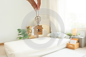 Moving house, relocation. man hold key house keychain in new apartment, inside the room was a cardboard box containing personal