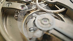 Moving metal gears inside working pocket watch mechanism. Working clock mechanism with rotating spring, gears, gearing