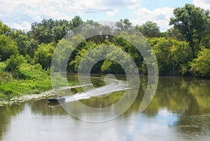 Moving on a motor boat on a river with forested coasts