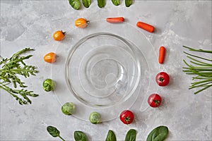 Moving multicolored natural fresh vegetables and cooking a healthy vegetarian salad in a glass bowl on a gray stone