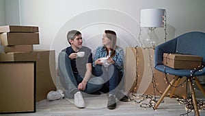 Moving into a new apartment. Young couple family drink tea or coffee, resting after unpacking boxes in the new house owners