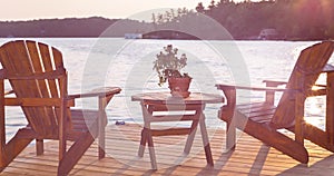 A moving picture of Muskoka chairs on a deck overlooking Lake Rosseau, Ontario, at sunset with sunflare.
