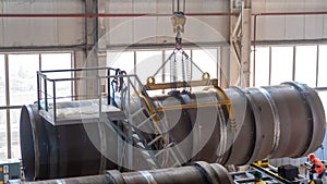 Moving pipes inside the workshop with an overhead crane using a traverse