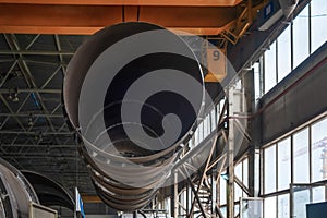 Moving pipes inside the workshop with an overhead crane using a traverse