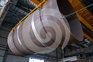 Moving pipes inside the workshop with an overhead crane using a traverse