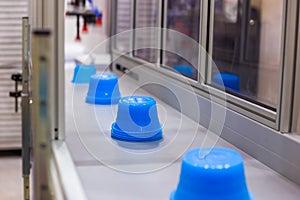 Pots on conveyor belt of plastic injection molding machine with robotic arm