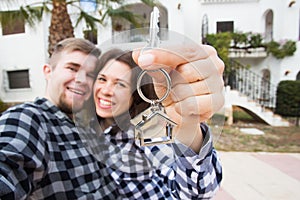 Moving and real estate concept - Happy young laughing cheerful couple man and woman holding their new home keys in front
